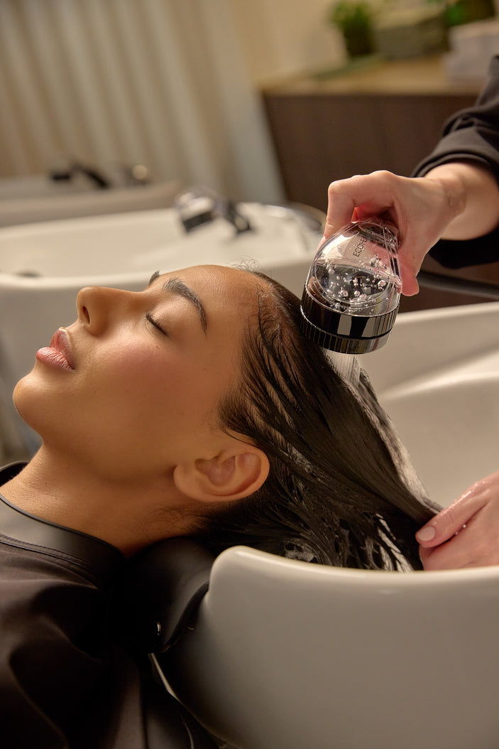 Stylist rinsing a client’s hair with the ECOHEADS Showerhead SP at a salon basin