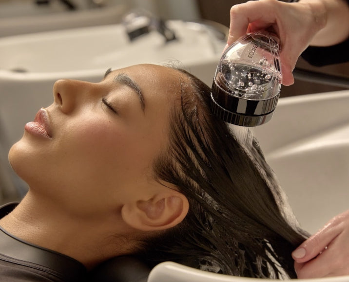 Client having their hair rinsed with an ECOHEADS showerhead