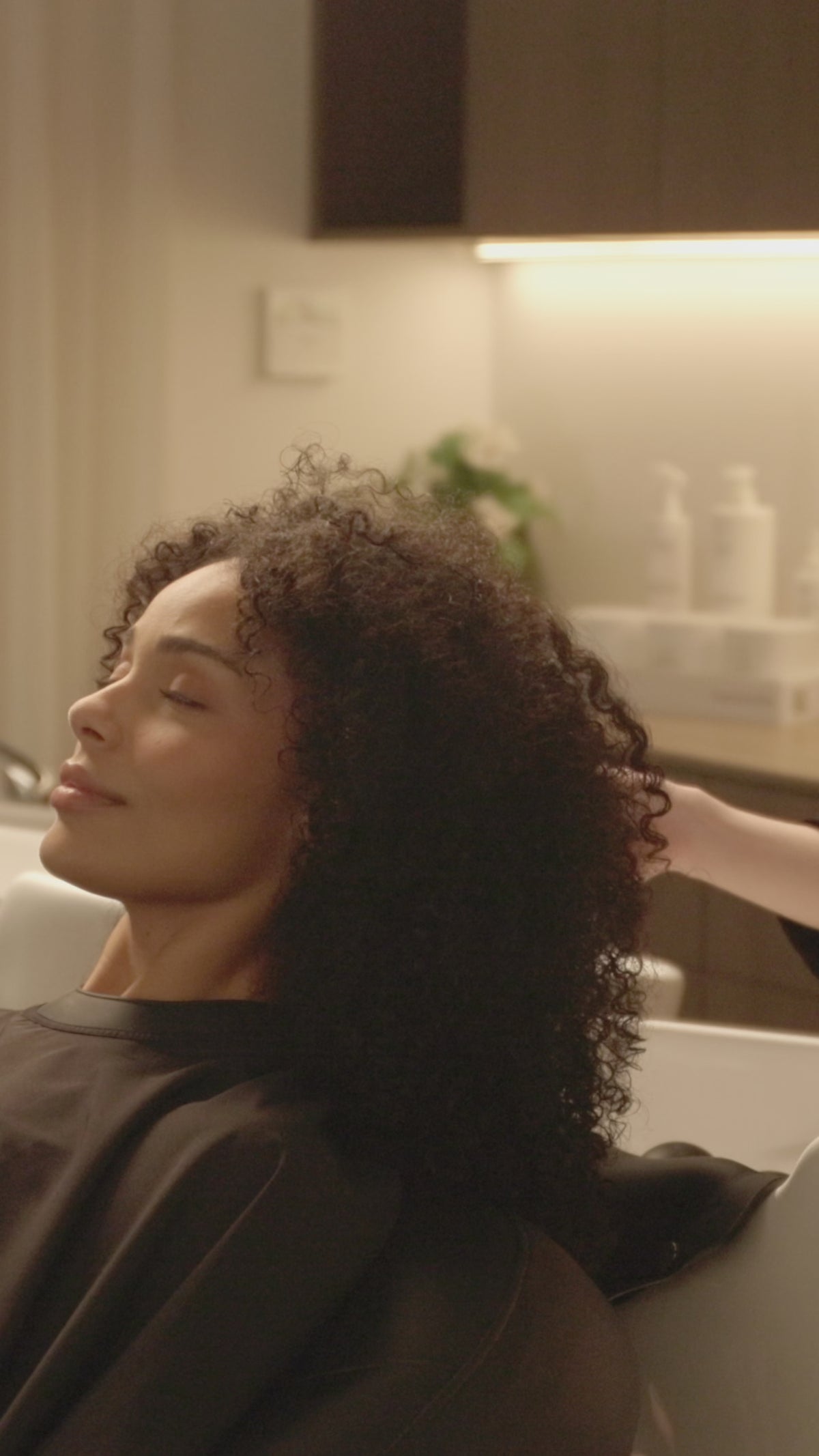 A salon client having their hair rinsed with the Ecoheads Showerhead SP